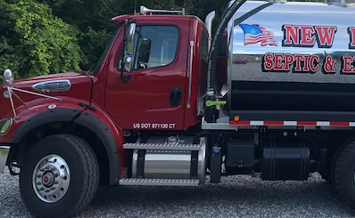 Close view of the red Freightliner cab, its chrome mirror and the front wheel,
              with the stainless tank behind it